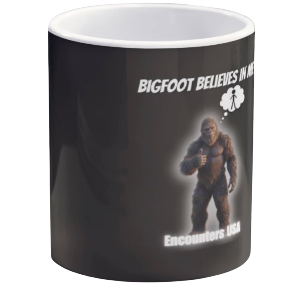 Black ceramic coffee mug with funny Bigfoot design saying "BIGFOOT BELIEVES IN ME" and a thumbs-up Sasquatch with thought bubble. Encounters USA merch.